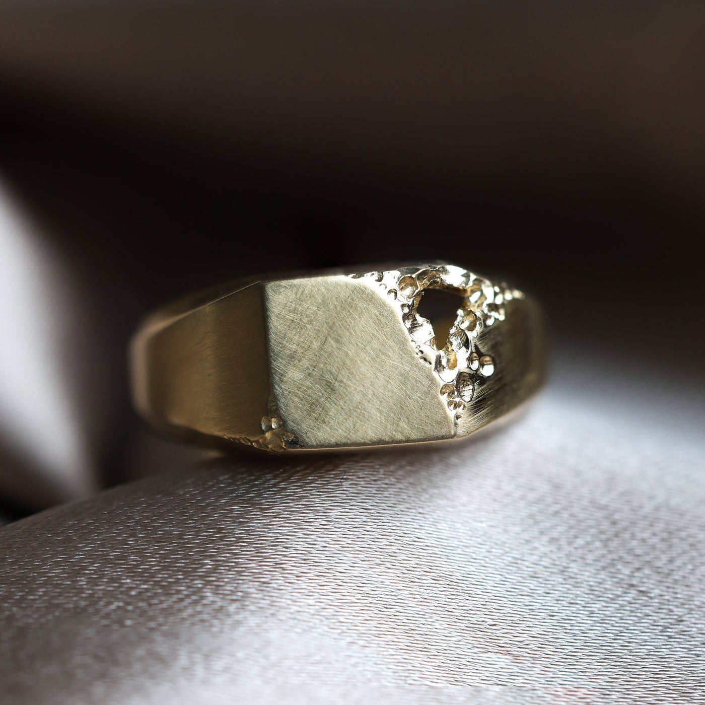 A gold signet ring with a central hole, polished finish, customizable gemstones, and band width of 9.3mm.