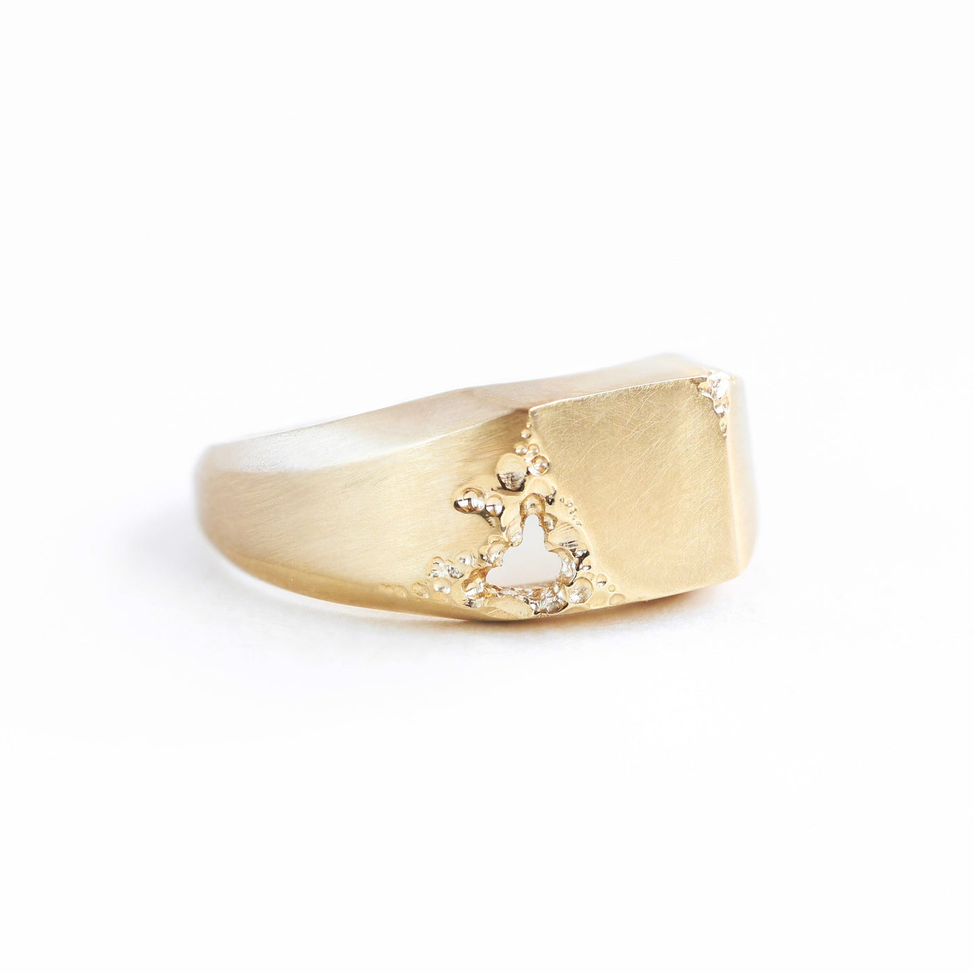 Men's gold signet ring with intricate cut-out design, polished finish, customizable gemstones.