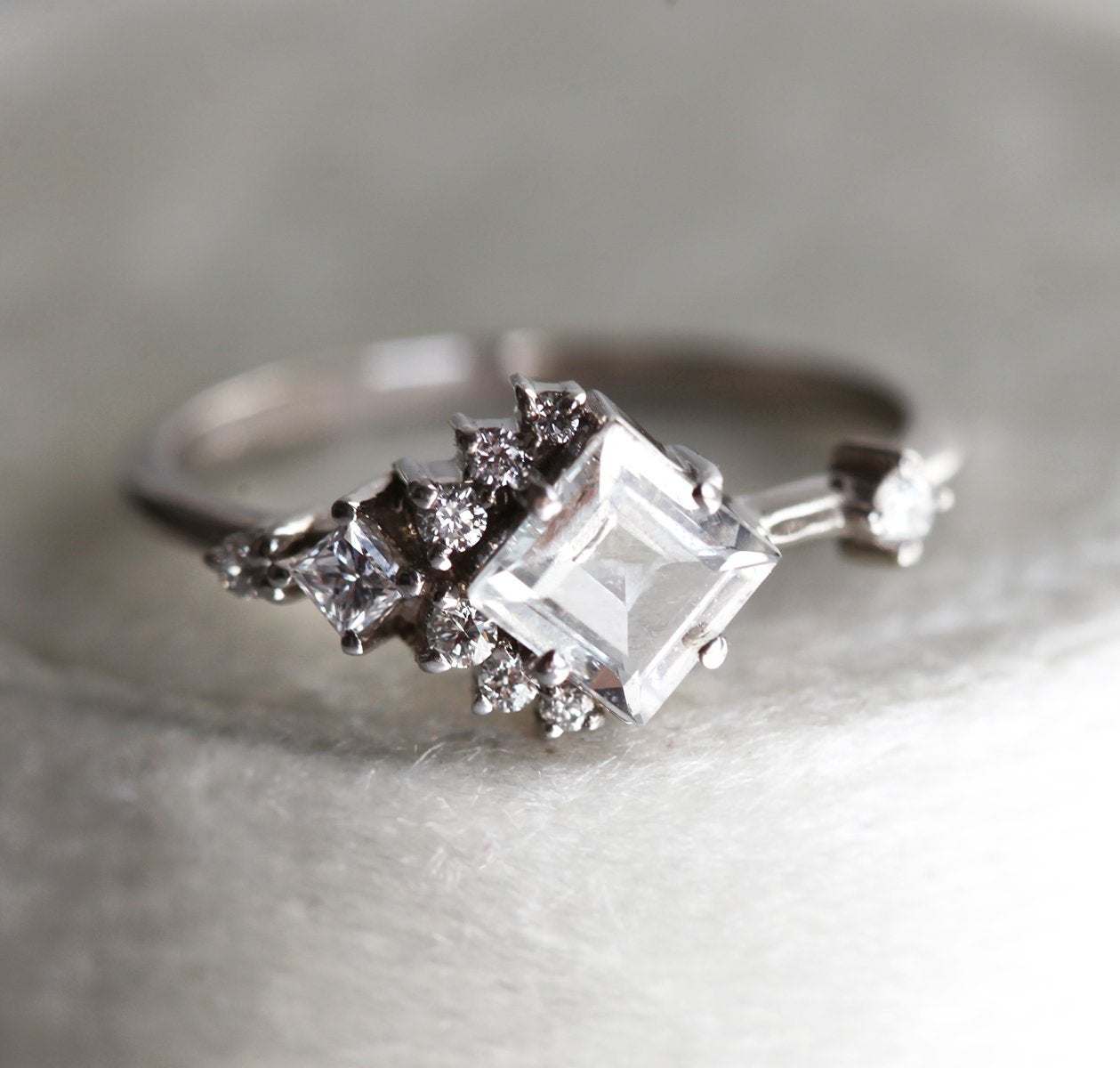 Square-shaped white sapphire ring with diamond cluster