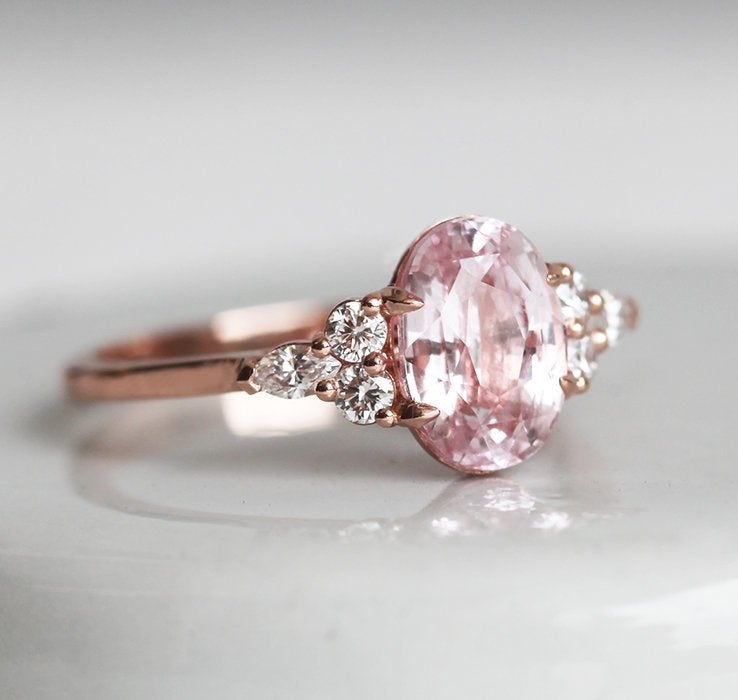 Oval-shaped peach sapphire ring with side diamonds