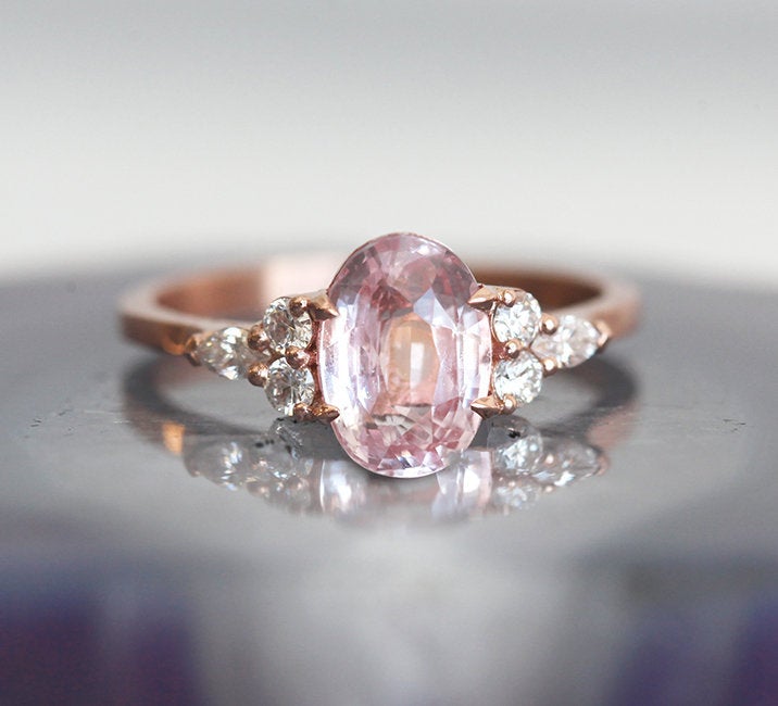 Oval-shaped peach sapphire ring with side diamonds