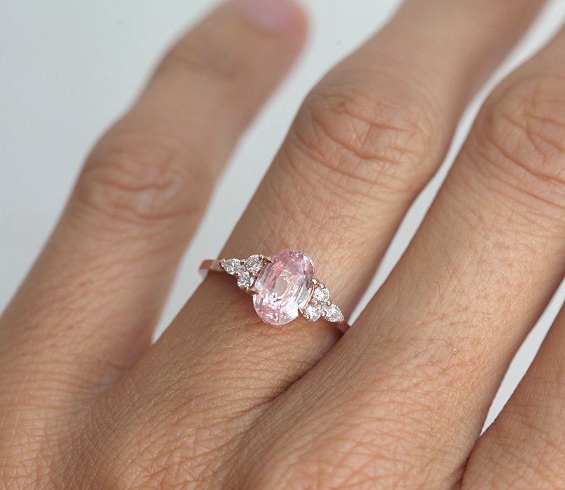 Oval-shaped peach sapphire ring with side diamonds