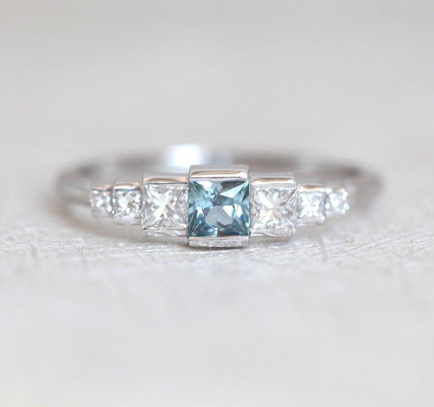 Princess-shaped teal sapphire ring with side diamonds