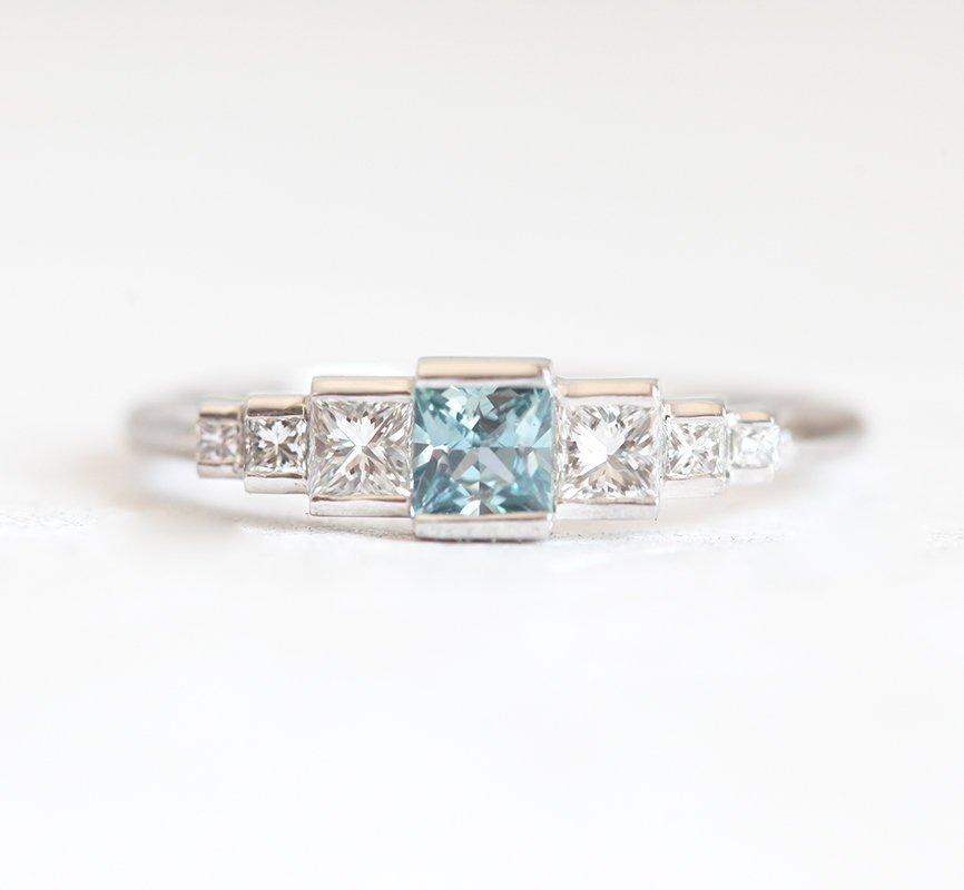 Princess-shaped teal sapphire ring with side diamonds