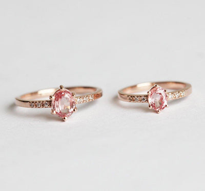 Two oval-shaped peach sapphire rings with side diamonds