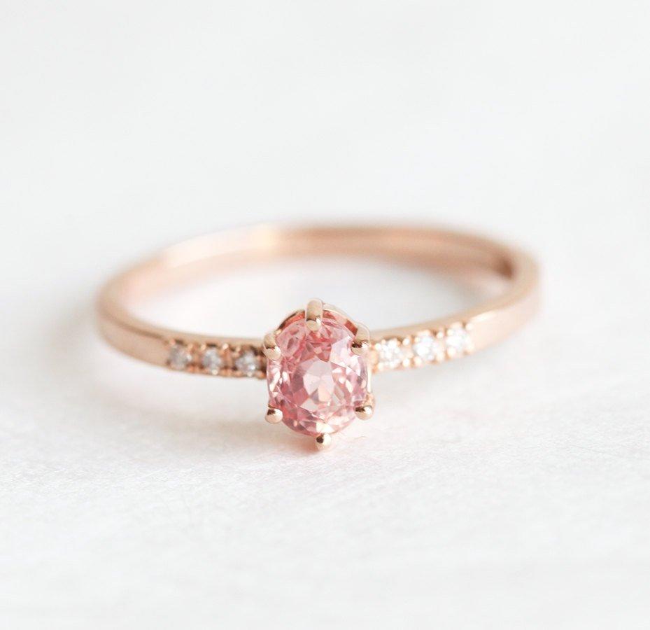 Oval-shaped peach sapphire ring with side diamonds