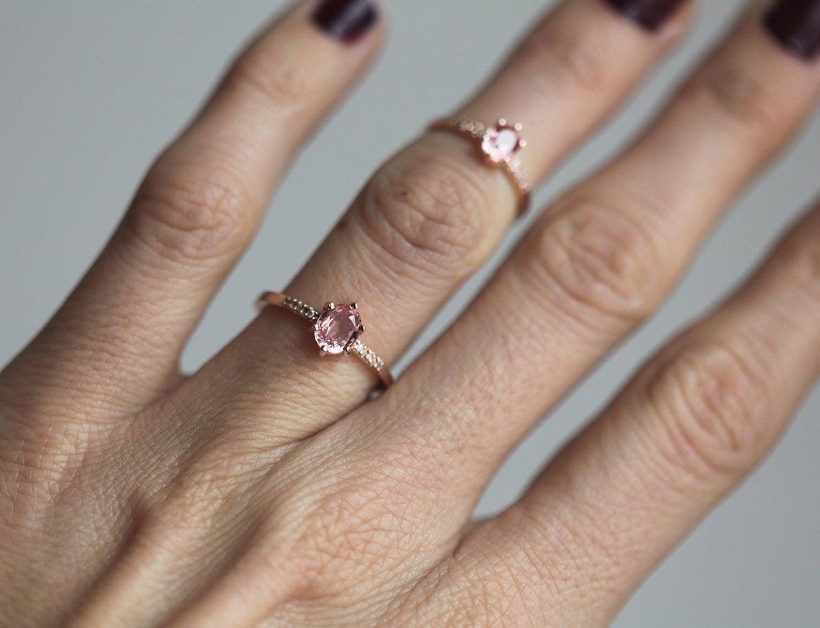 Two oval-shaped peach sapphire rings with side diamonds