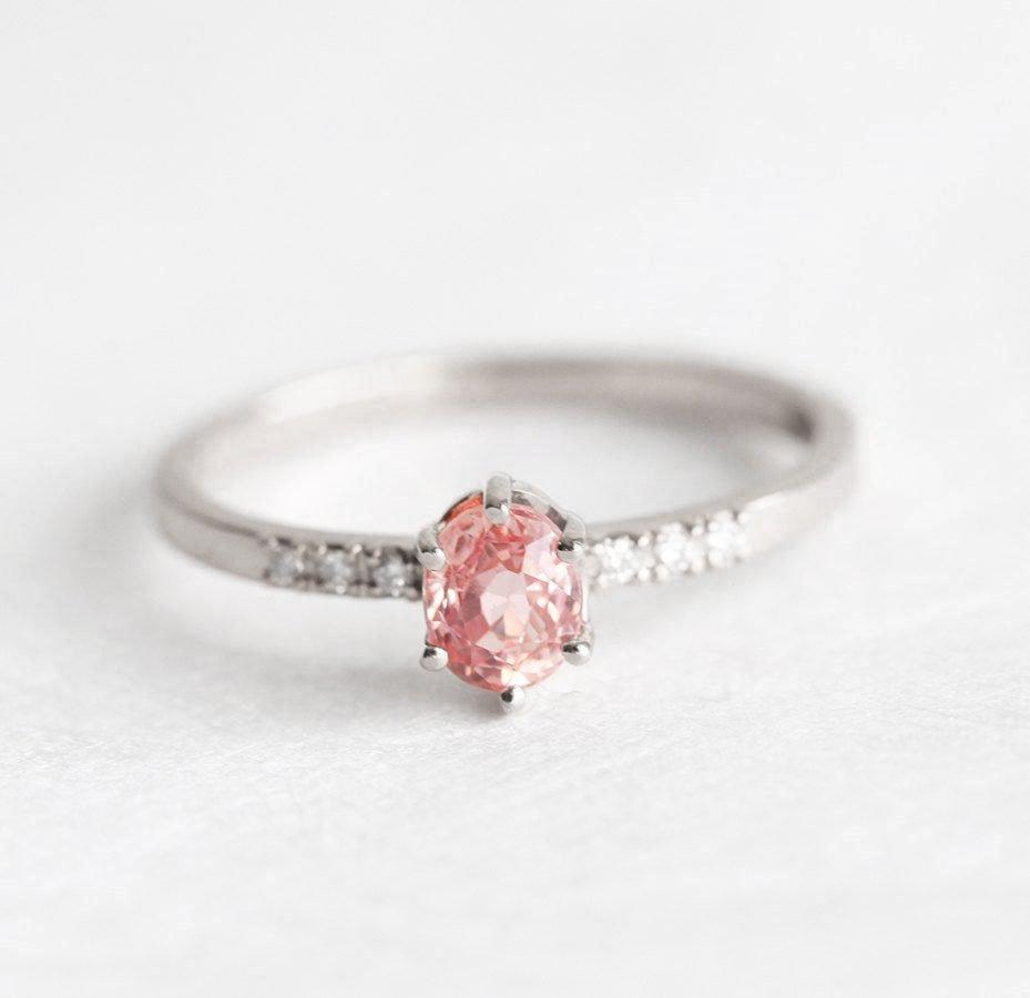 Oval-shaped peach sapphire ring with side diamonds