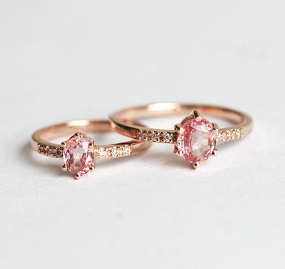 Two oval-shaped peach sapphire rings with side diamonds