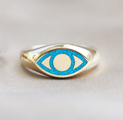 Gold signet ring with turquoise inlay, featuring an all-seeing eye design. Unisex, polished finish, customizable gemstones. Made of 14k or 18k gold, platinum options available.