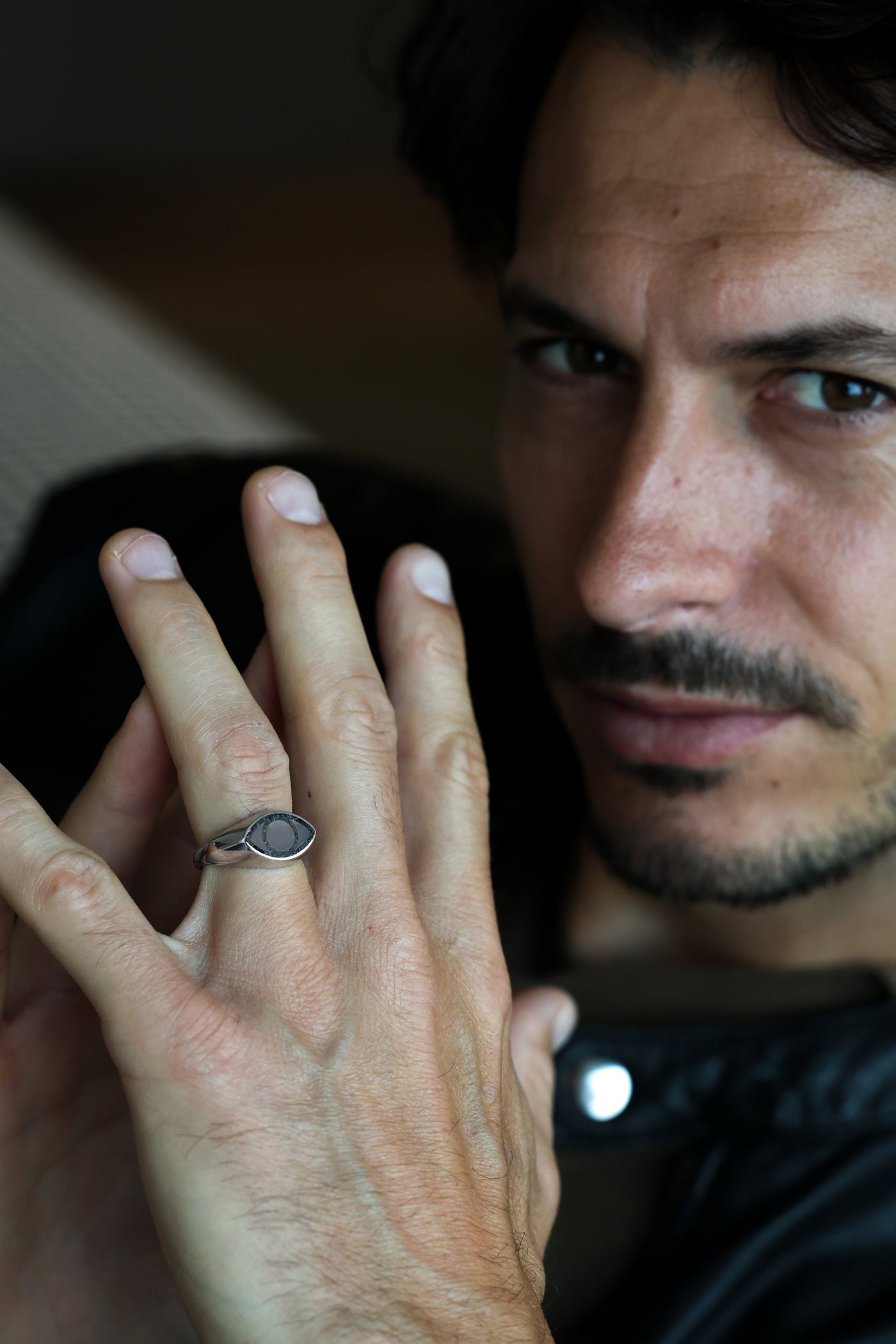 A close-up of a person's hand wearing an All Seeing Eye black spinel inlay signet ring.