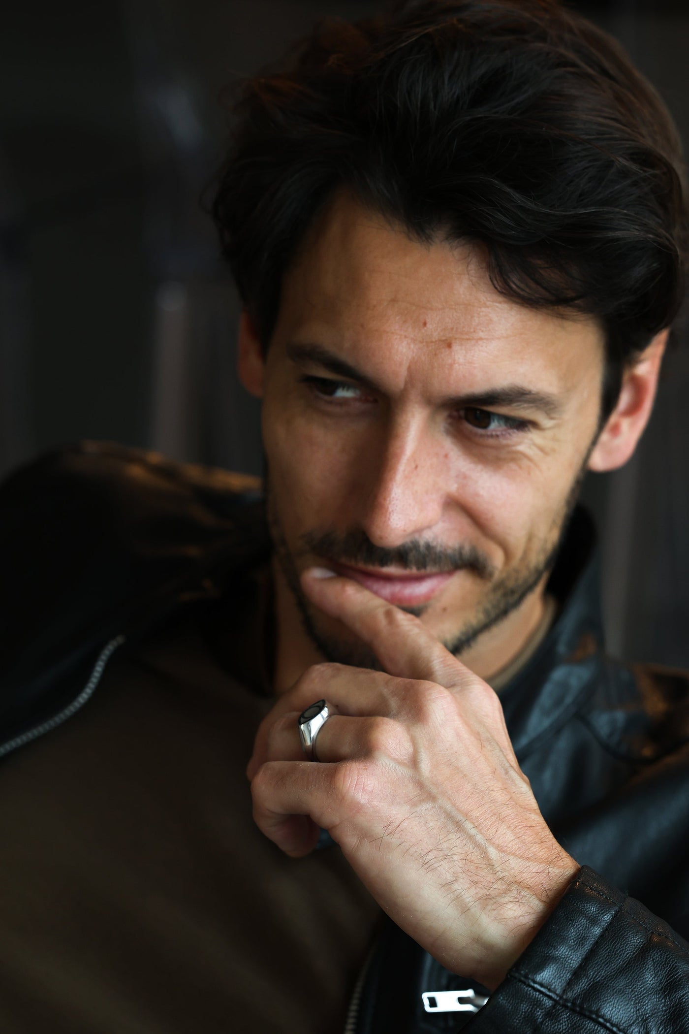 A man's hand wearing a black spinel inlay signet ring.