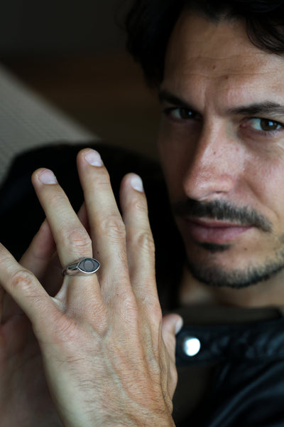 A close-up of a person's hand wearing an All Seeing Eye black spinel inlay signet ring.