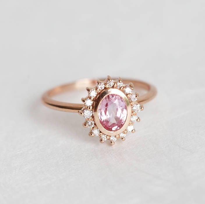 Pink oval-shaped sapphire halo ring with side diamonds