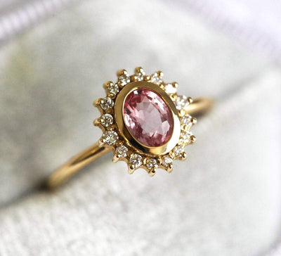 Pink oval-shaped sapphire halo ring with side diamonds