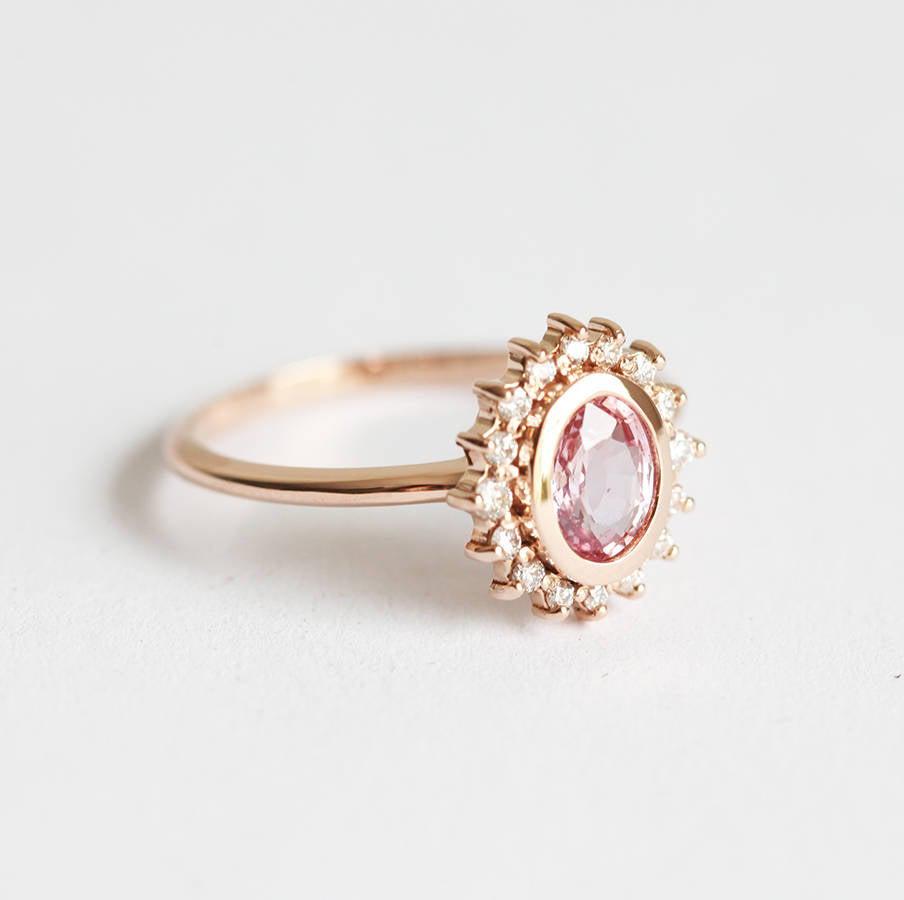 Pink oval-shaped sapphire halo ring with side diamonds