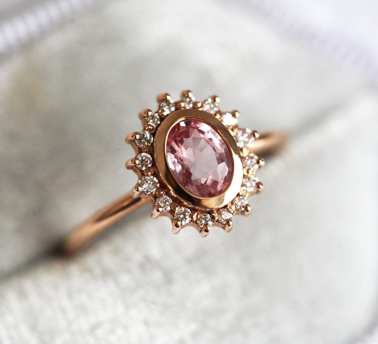 Pink oval-shaped sapphire halo ring with side diamonds