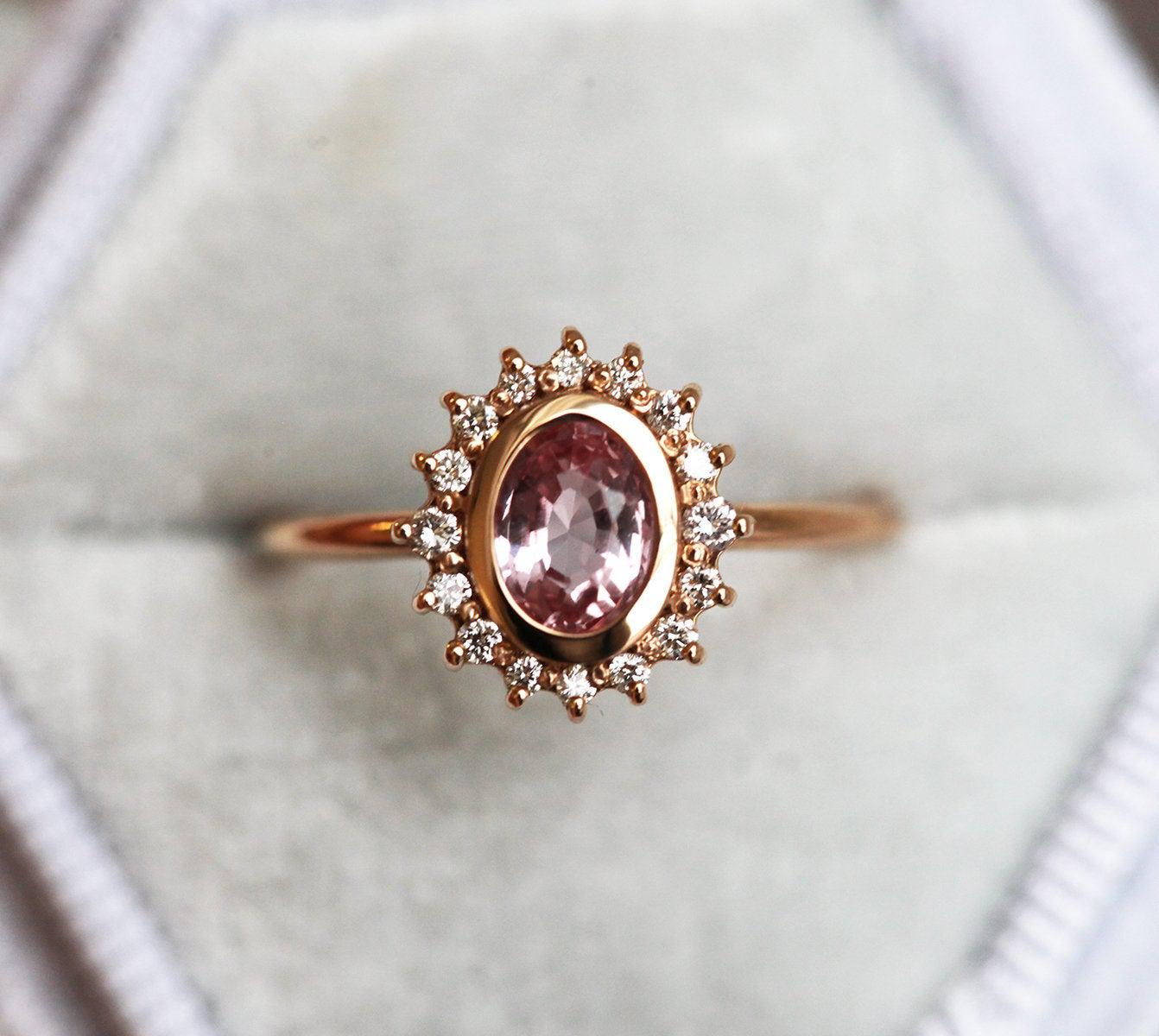 Pink oval-shaped sapphire halo ring with side diamonds