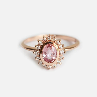 Pink oval-shaped sapphire halo ring with side diamonds