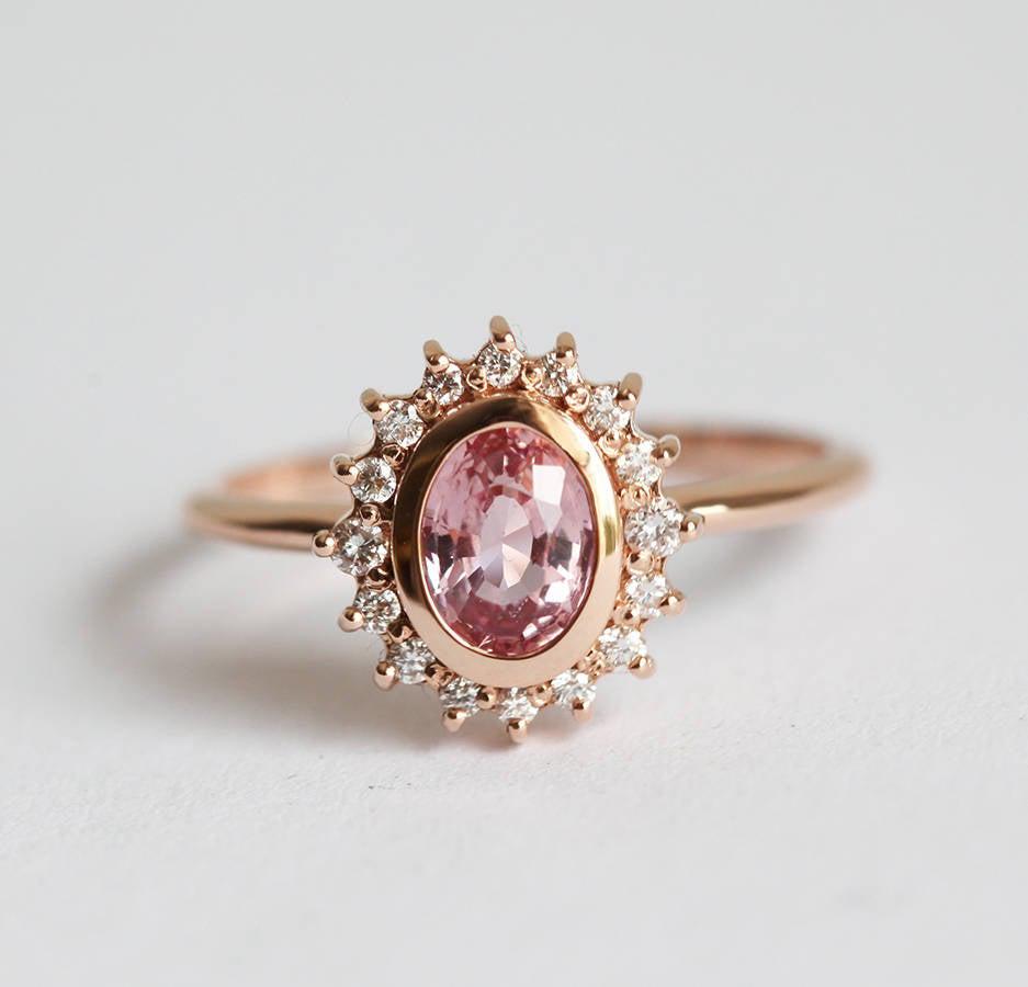 Pink oval-shaped sapphire halo ring with side diamonds