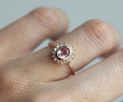 Pink oval-shaped sapphire halo ring with side diamonds