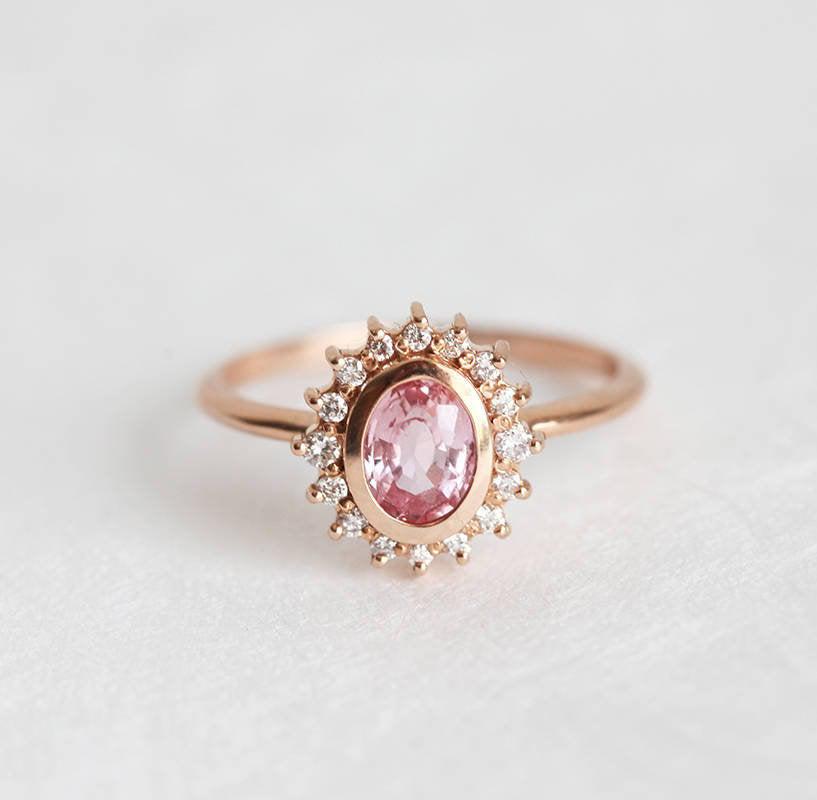 Pink oval-shaped sapphire halo ring with side diamonds