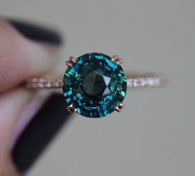 Teal-colored round sapphire ring with side diamonds