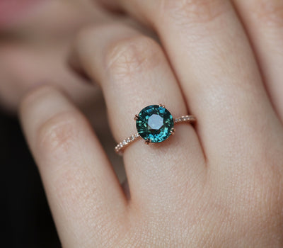 Teal-colored round sapphire ring with side diamonds