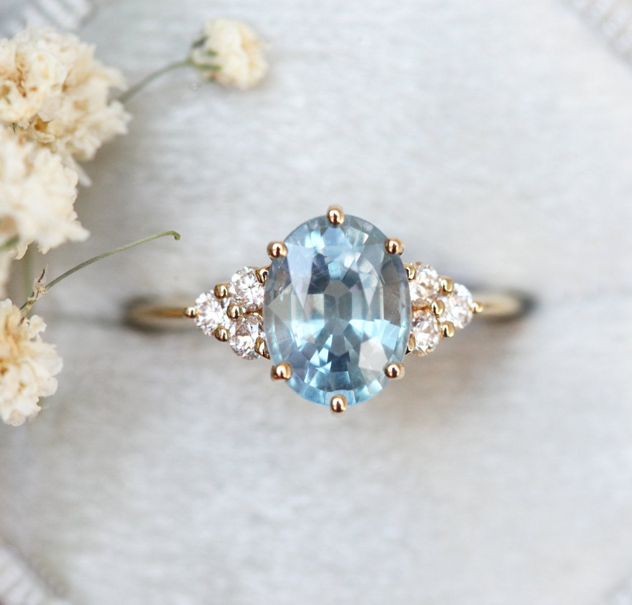 Light blue oval-shaped sapphire ring with diamond nesting
