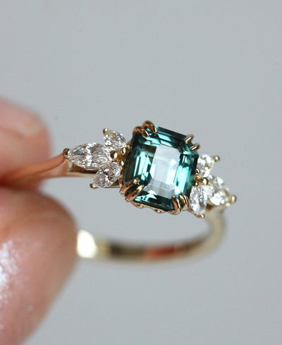 Emerald-shaped teal sapphire ring with diamond cluster