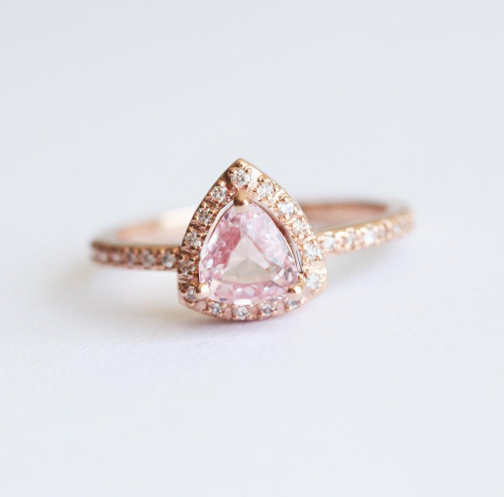 Trillion-shaped peach pink sapphire ring with diamond halo