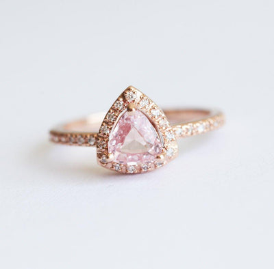 Trillion-shaped peach pink sapphire ring with diamond halo