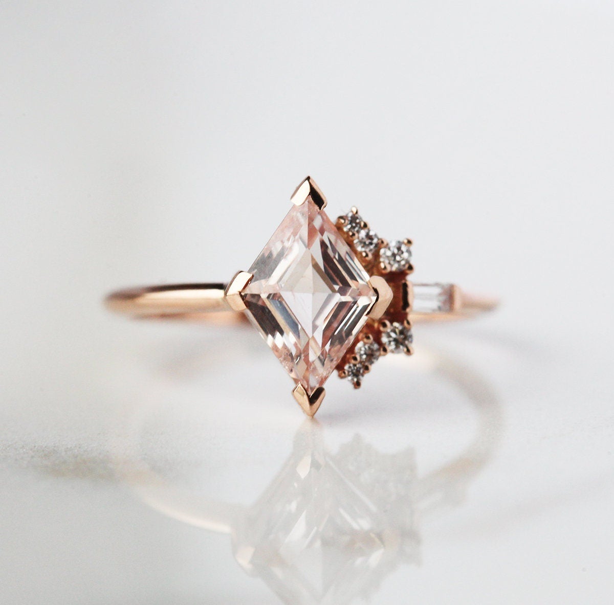Kite-shaped peach sapphire ring with diamond cluster