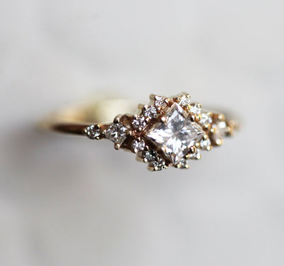 Gold ring with princess cut diamond centerpiece and side diamond clusters