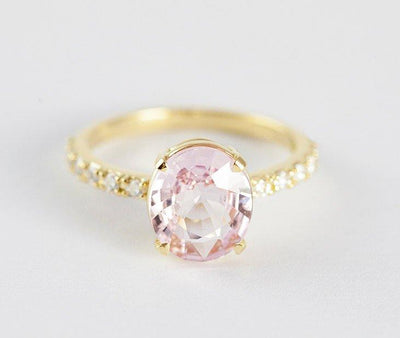 Oval-shaped light peach pink sapphire ring with side diamonds