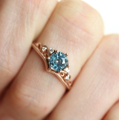 Round teal sapphire ring with white side diamonds