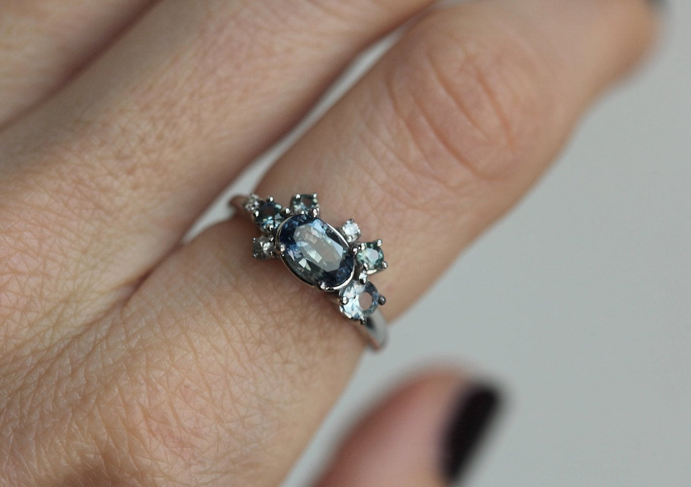 Blue oval-shaped sapphire ring with diamond cluster