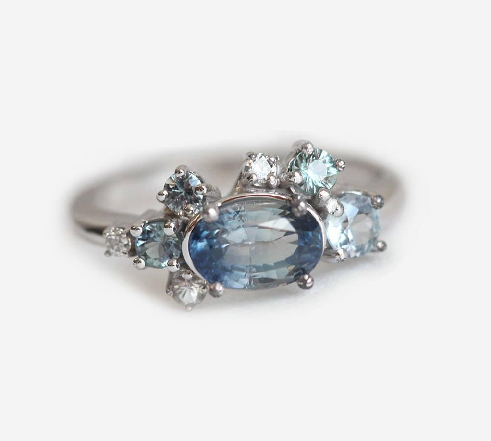 Blue oval-shaped sapphire ring with diamond cluster
