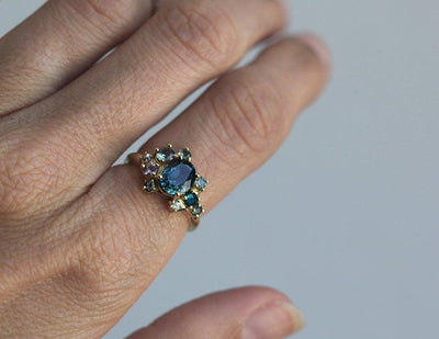 Blue oval-shaped sapphire ring with diamond cluster