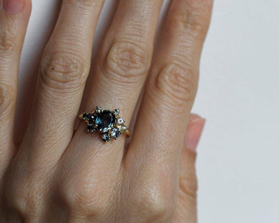 Blue oval-shaped sapphire ring with diamond cluster