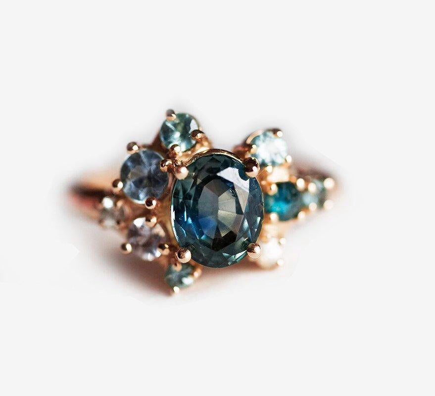 Blue oval-shaped sapphire ring with diamond cluster