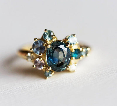 Blue oval-shaped sapphire ring with diamond cluster