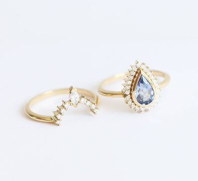 Pear-shaped blue sapphire ring with diamond halo and matching diamond band
