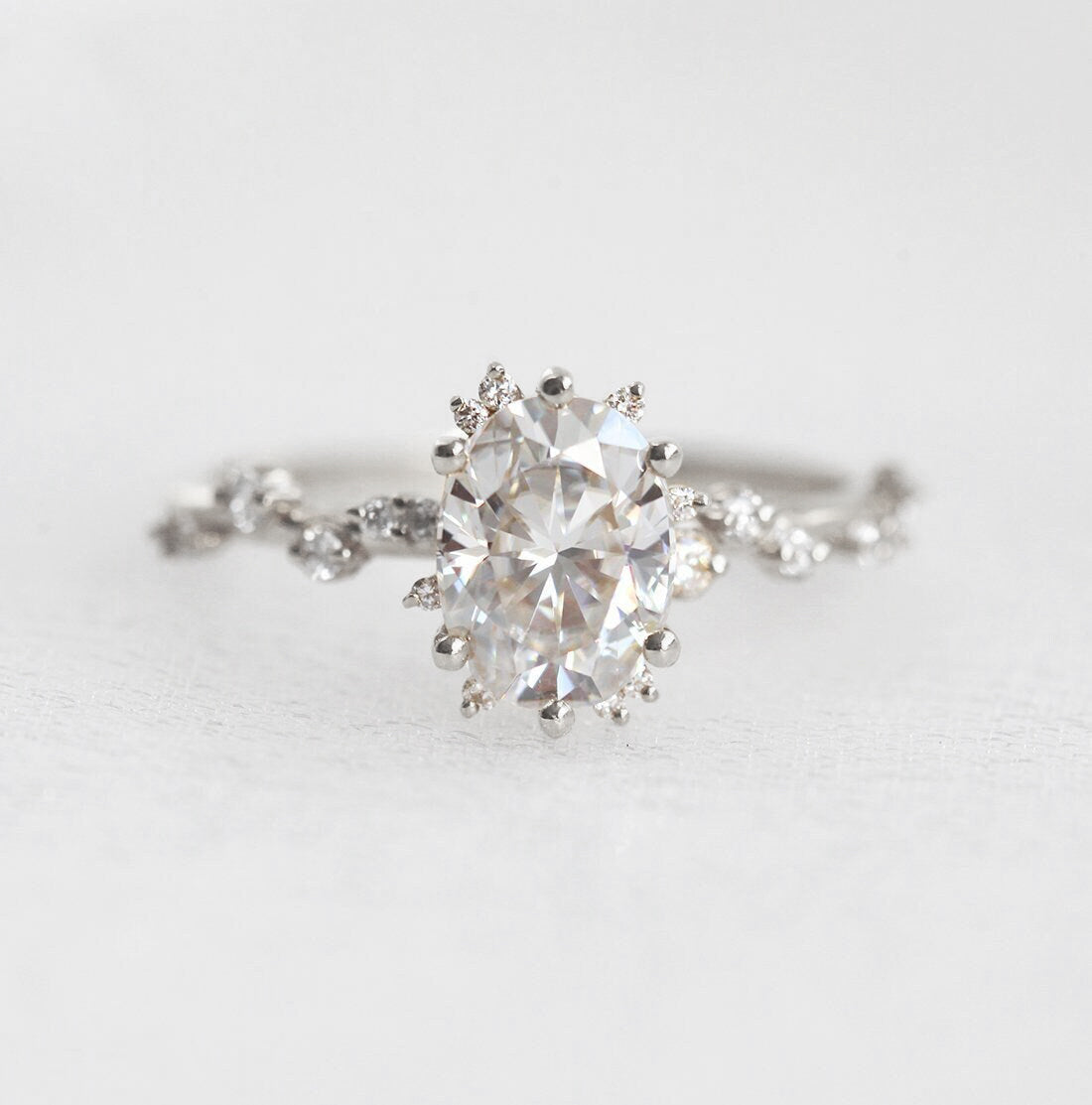 Oval White Diamond Cluster Ring with Side White Round Diamonds Placed like a vine leading to the center stone