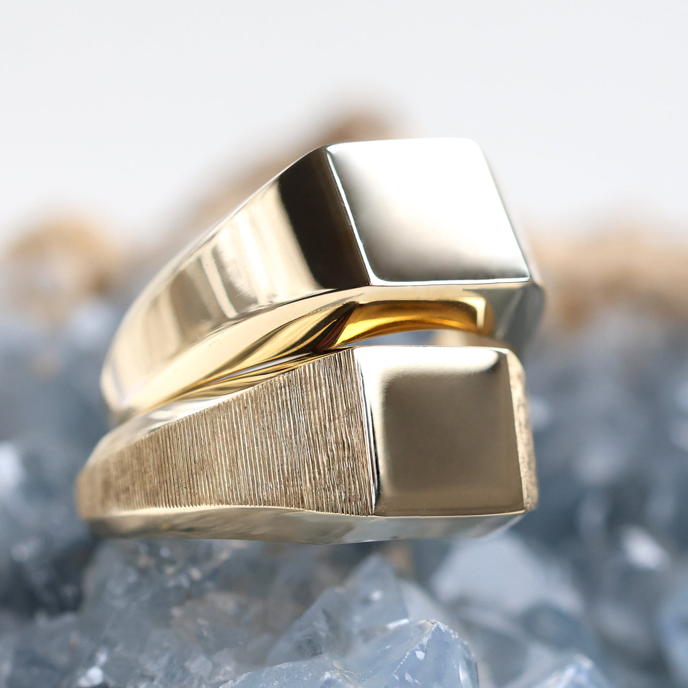 A close-up of a gold signet ring on a rock, showcasing premium metals like sterling silver, solid gold, and platinum. Customizable with gemstones.