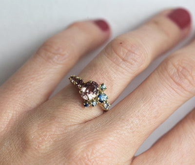 Oval-shaped peach sapphire and diamond cluster ring