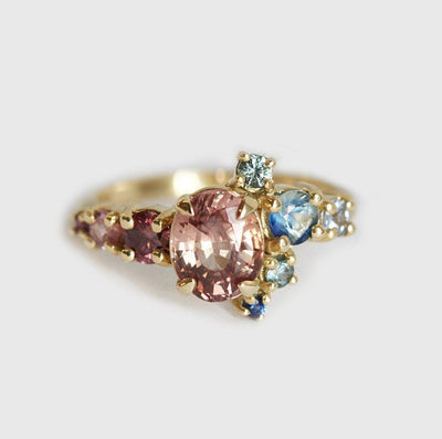 Oval-shaped peach sapphire and diamond cluster ring