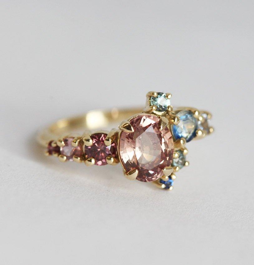 Oval-shaped peach sapphire and diamond cluster ring