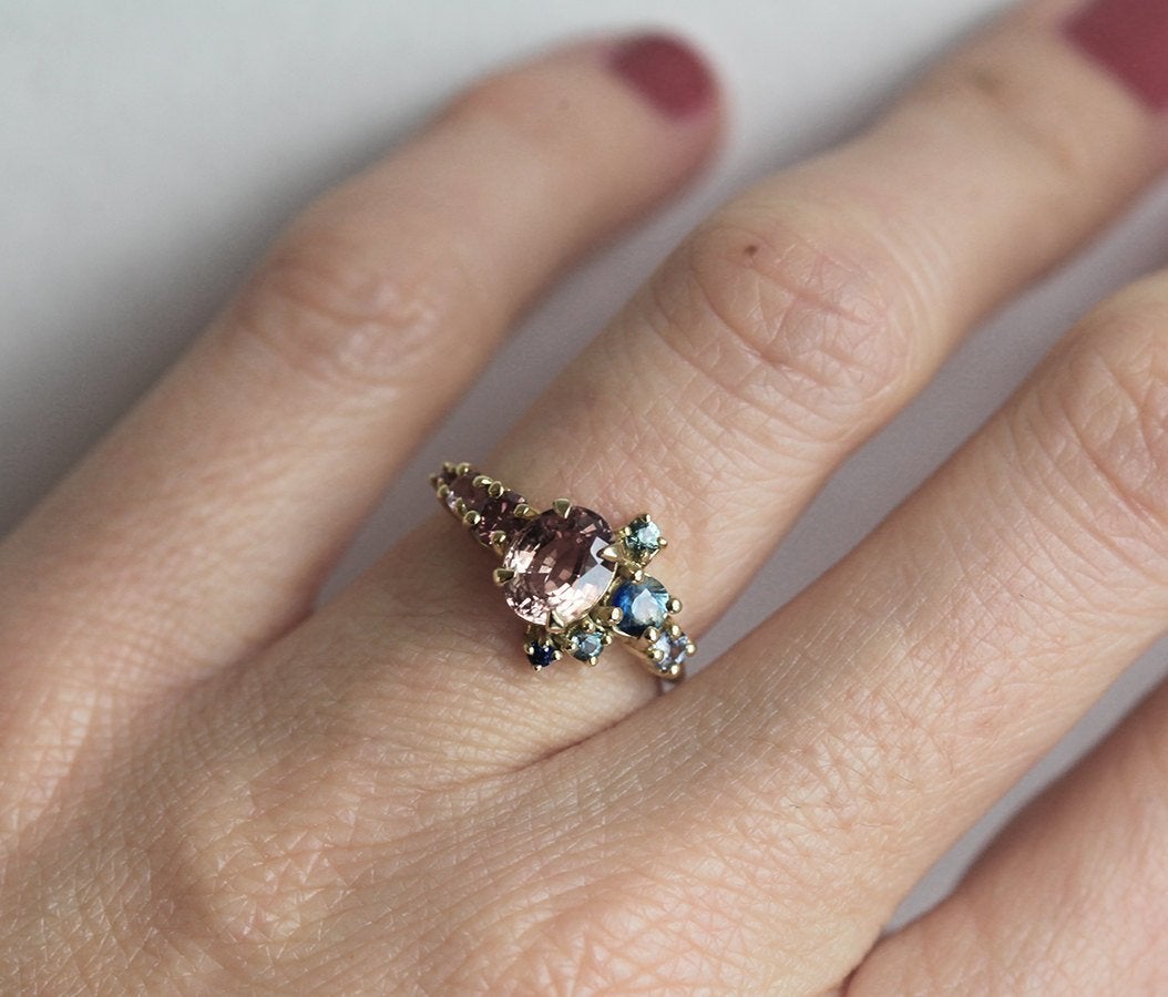 Oval-shaped peach sapphire and diamond cluster ring