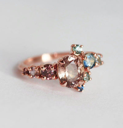 Oval-shaped peach sapphire and diamond cluster ring